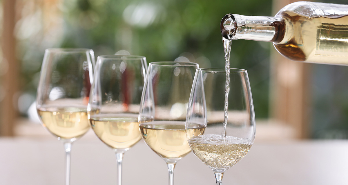 Understanding white wine showing a bottle pouring white wine into four glasses